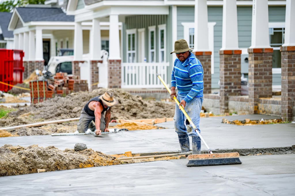 Concreter broom-finishing a freshly poured concrete slab