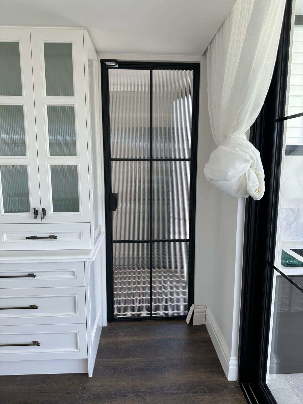 Black steel-framed glass door in a laundry